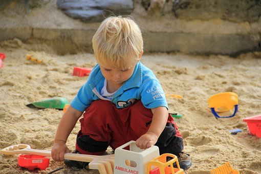 Child Playing in Sand with Toy Vehicles